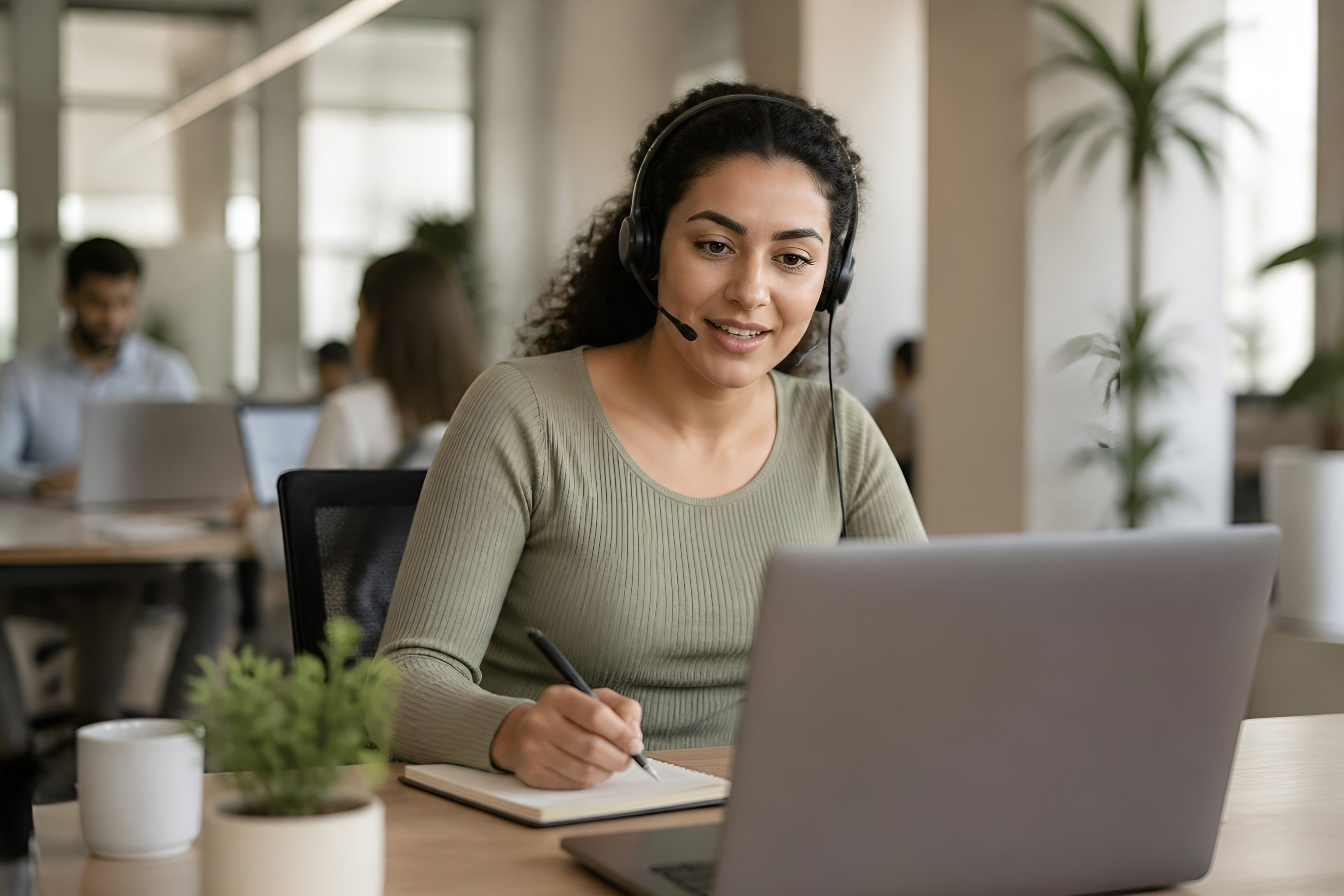 Support specialist on a headset taking notes for a customer